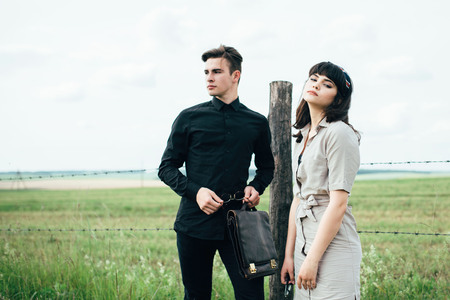 Cute young guy standing next to a beautiful girl on a green background behind a city.の写真素材