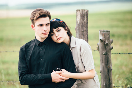 Cute young guy standing next to a beautiful girl on a green background behind a city.の写真素材