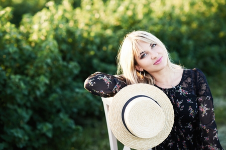 Cute young blond girl sits on a chair against green background.の写真素材
