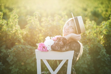Cute young blond girl sits on a chair against green background with pions in her hands.の写真素材