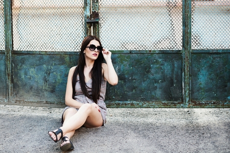 A cute young brunette girl in a local style near the old fenceの写真素材