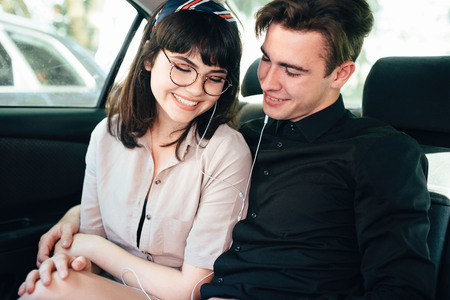 Beautiful guy with a girl hugging, sitting on the car, smile.の写真素材