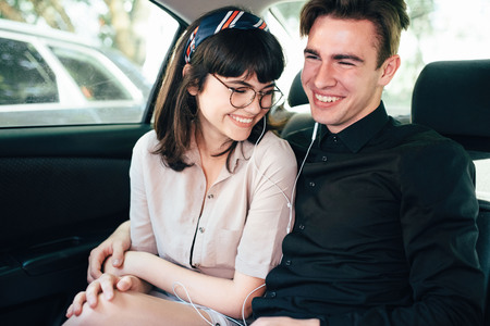 Beautiful guy with a girl hugging, sitting on the car, smile.の写真素材