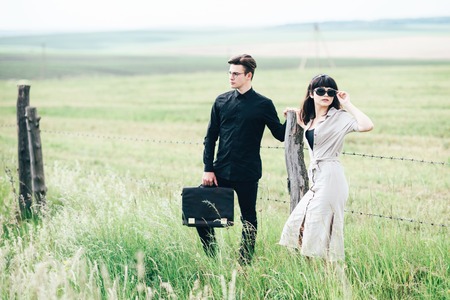 Cute young guy standing next to a beautiful girl on a green background behind a city.の写真素材