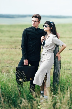 Cute young guy standing next to a beautiful girl on a green background behind a city.の写真素材