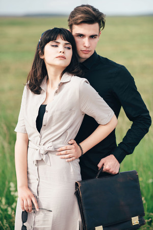 A cute young guy stands next to a pretty girl in whose hands a business bag.の写真素材