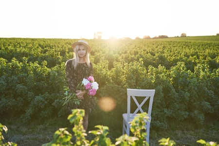 Cute young blond girl sits on a chair against green background with pions in her hands.の写真素材
