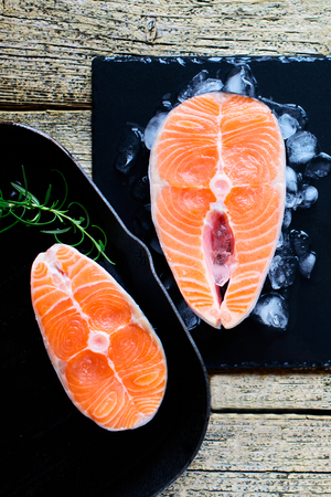 Two salmon steaks are ready to cook on a grill, along with lime on a wooden background. Top view. Healthy food.の写真素材