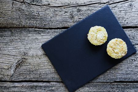 Two muffins, covered with shtryzelem, and with cheese cream on a black board on a wooden background.の写真素材