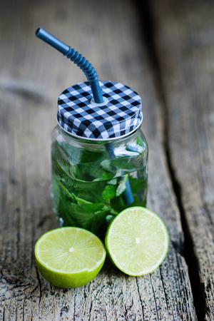 Citrus fruit and herbs infused sassi water for detox or dieting in glass bottles on wooden board, dark background.の写真素材