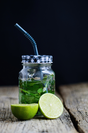 Citrus fruit and herbs infused sassi water for detox or dieting in glass bottles on wooden board, dark background.の写真素材
