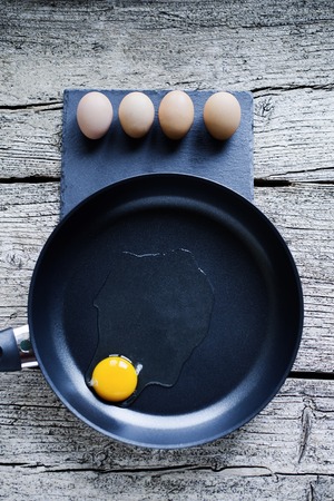 Cooking eggs on a frying pan from a non-stick material on a wooden background.の写真素材
