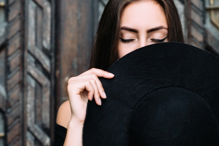 Portrait of a young pretty girl with a black hat in her arms.の写真素材