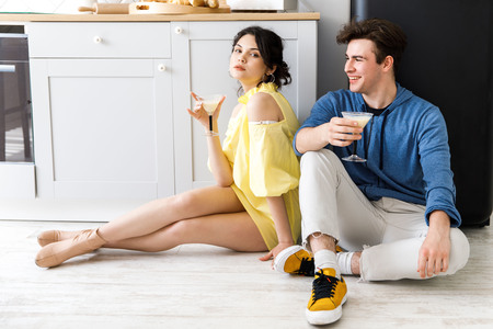 Young cute couple - a boy and a girl, having fun in the kitchen, drinking cocktails.の写真素材