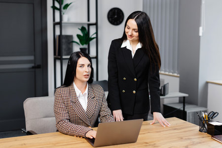 Call center agent with headset working on support hotline in modern office. Two young attractive women are working in the office.の写真素材