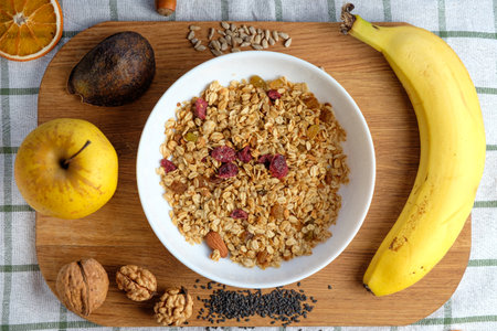 Healthy breakfast - granola with nuts, seeds and fruits on wooden board