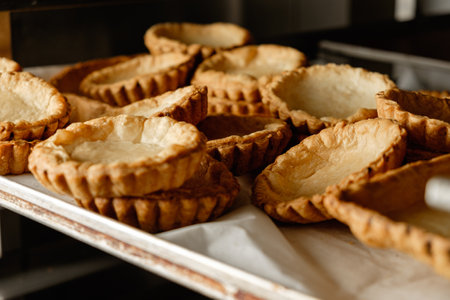 Freshly baked pastry shells cooling on a baking tray in a cozy kitchen setting during early morning...