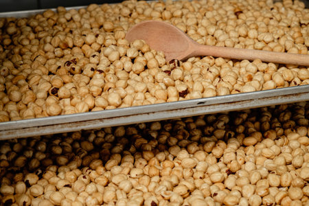 Roasted nuts on display in a marketplace, showcasing a variety of textures and colors under soft natural lightingの写真素材