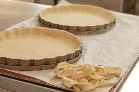 Crafting perfect pastry shells in a bustling kitchen setting where bakers prepare for a delightful dessert creationの写真素材