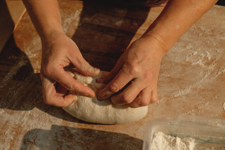 Kneading dough with care in a sunlit kitchen, capturing the essence of homemade cooking and traditional recipes from a family heritageの写真素材