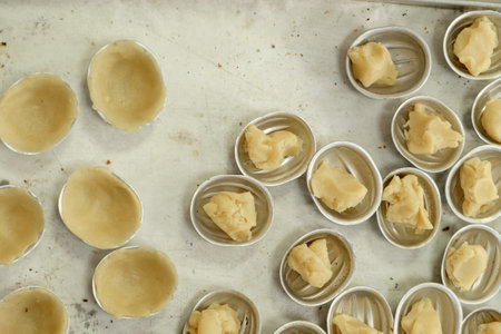 Delicate pastries sit in metal nut molds, awaiting the magic of transformation in a warm, cozy kitchen.の写真素材