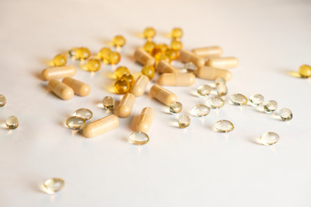 Different shapes and colors of dietary supplements scattered on a white surfaceの写真素材