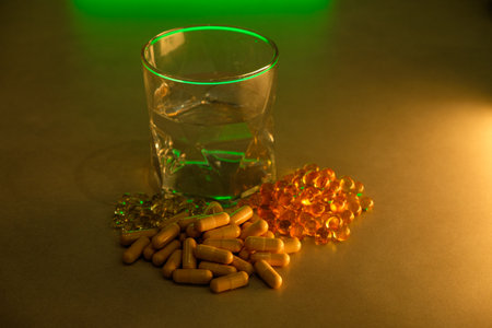 Vibrant capsules and a glass of water highlight health and wellnessの写真素材