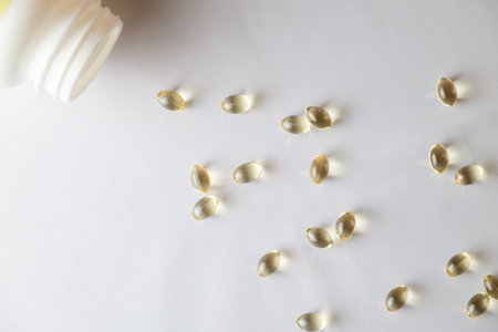 Soft gel capsules scattered on a surface near an overturned bottle