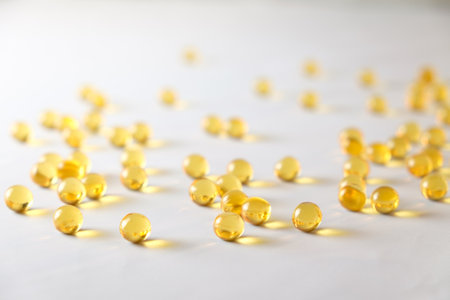 Vibrant golden capsules scattered on a white surface attract attentionの写真素材