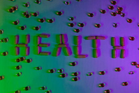 Creative arrangement of capsules spelling health against a colorful backdropの写真素材