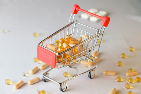 Tiny shopping cart filled with vibrant capsules on a clean surfaceの写真素材