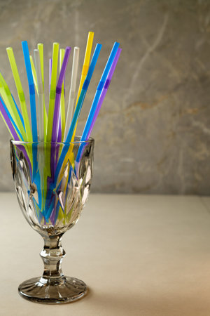 Colorful straws arranged in a crystal glass on a marble tabletopの写真素材