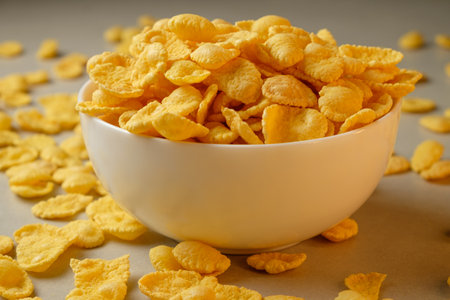Crunchy corn flakes spilling from a bowl on a kitchen counterの写真素材