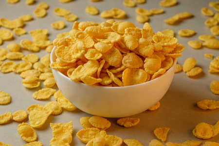 Delightful corn flakes scattered around a bowl in a cozy breakfast settingの写真素材
