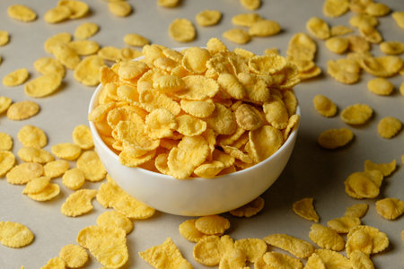 Delightful bowl of golden flakes surrounded by scattered cerealの写真素材