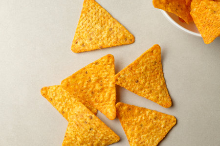 Colorful nachos chips scattered on a table create a lively snack environmentの写真素材
