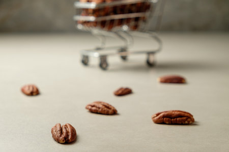 Delightful pecan nuts scattered near a shopping cart filled with moreの写真素材