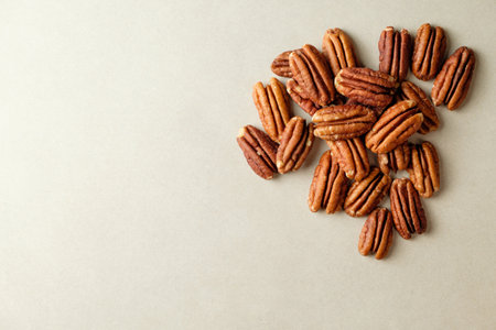 Delightful pecan nuts scattered on a soft beige backgroundの写真素材