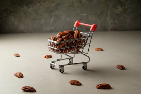 Shopping cart filled with pecan nuts on a minimalistic surfaceの写真素材