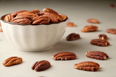Fresh pecan nuts collected and displayed in a bowl on a soft surfaceの写真素材