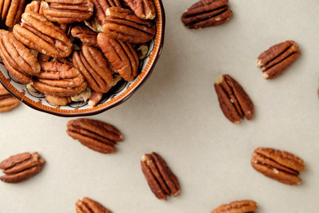 Delicious pecan nuts scattered around a rustic bowl on a calming surfaceの写真素材