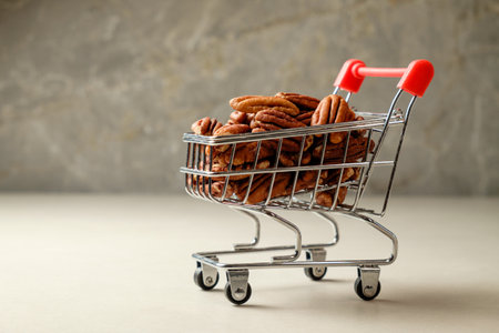 Pecan nuts piled high in a miniature shopping cart on a smooth surfaceの写真素材