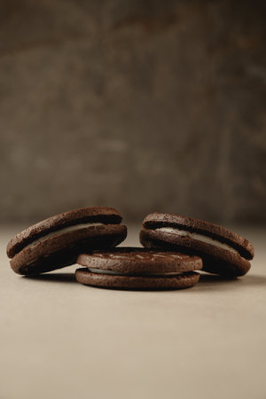 Delicious dark chocolate cookies stacked on a rustic surface in warm lightの写真素材
