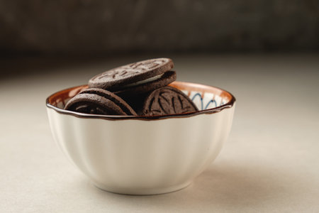 Deliciously stacked cocoa cookies in a decorative bowl await a sweet momentの写真素材
