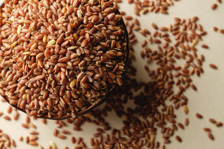 Organic brown rice overflowing from a rustic bowl on a wooden surfaceの写真素材