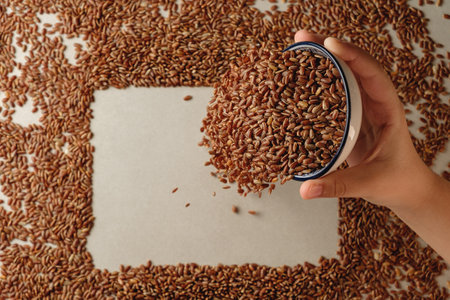 Hand pouring organic brown rice into a decorative arrangement on paperの写真素材