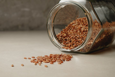 Sustainable brown rice spilling from a glass jar on a textured countertopの写真素材