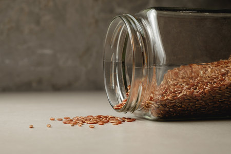 Brown rice spilling from a jar on a rustic kitchen countertopの写真素材