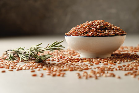 Organic brown rice in a rustic bowl with rosemary on a textured surfaceの写真素材