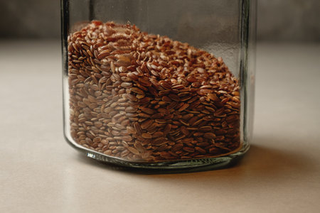 Brown rice stored in a glass jar with earthy tones and texturesの写真素材